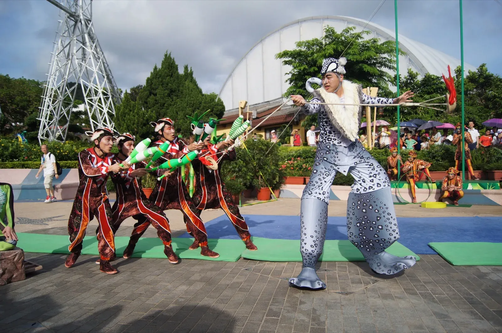 Bamboo Jam acrobats and a giant silver stilts character performing outdoors in Hong Kong