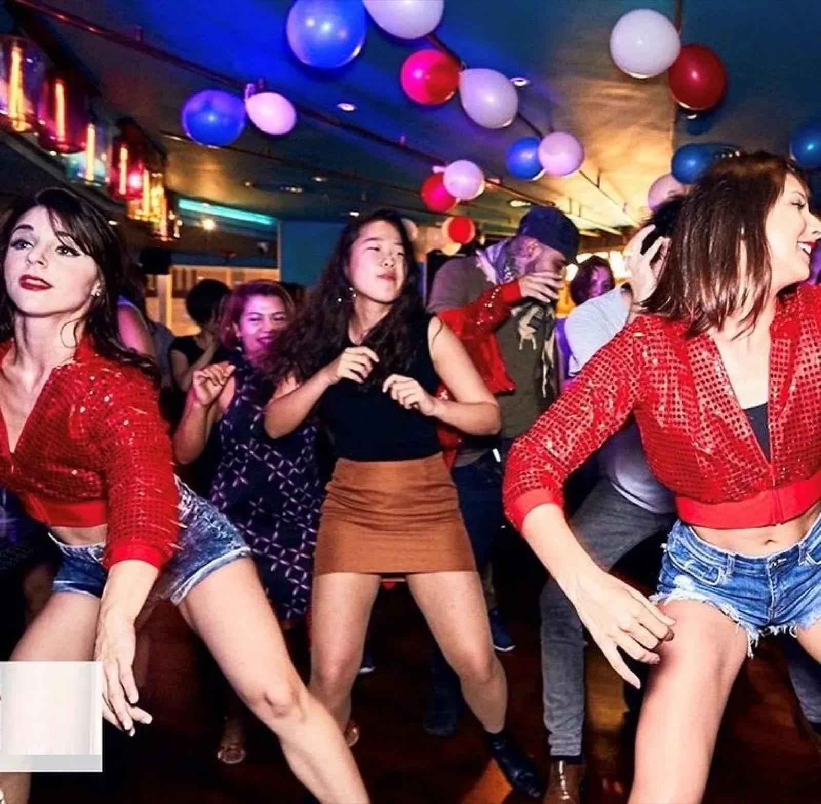 Professional dancers in red sequin tops dancing with guests at an office party in Hong Kong