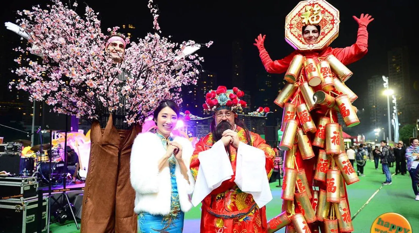 Chinese New Year characters, a blossom tree and a firecracker costume, posing with guests at a night event