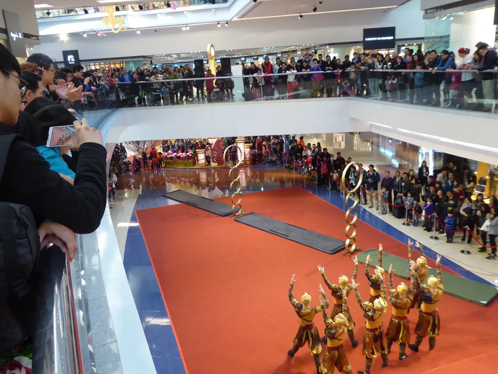 Acrobatic troupe in gold costumes performing for a Chinese New Year crowd at Festival Walk, Hong Kong