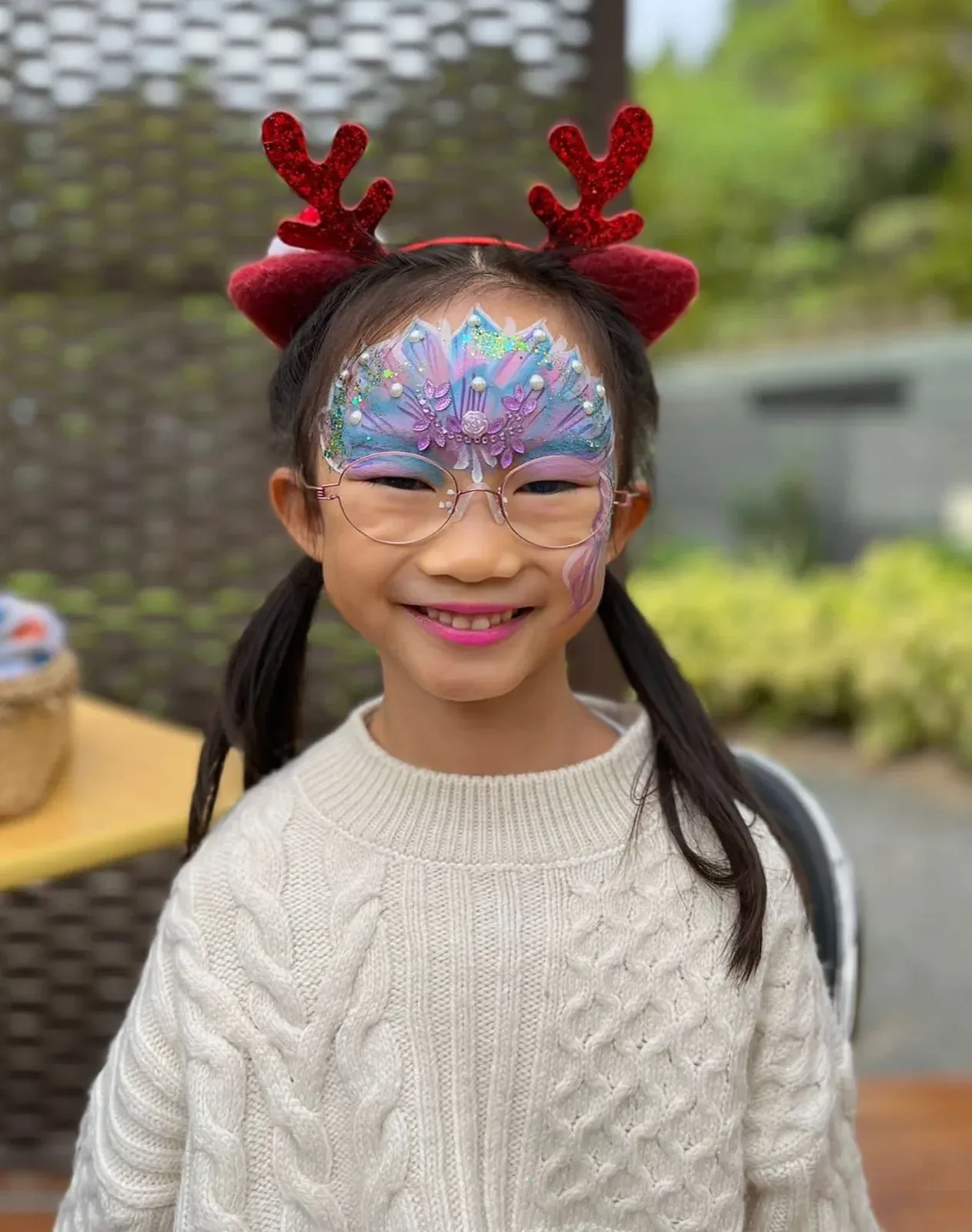 Girl with reindeer antlers and sparkly Christmas face paint at a children's party in Hong Kong