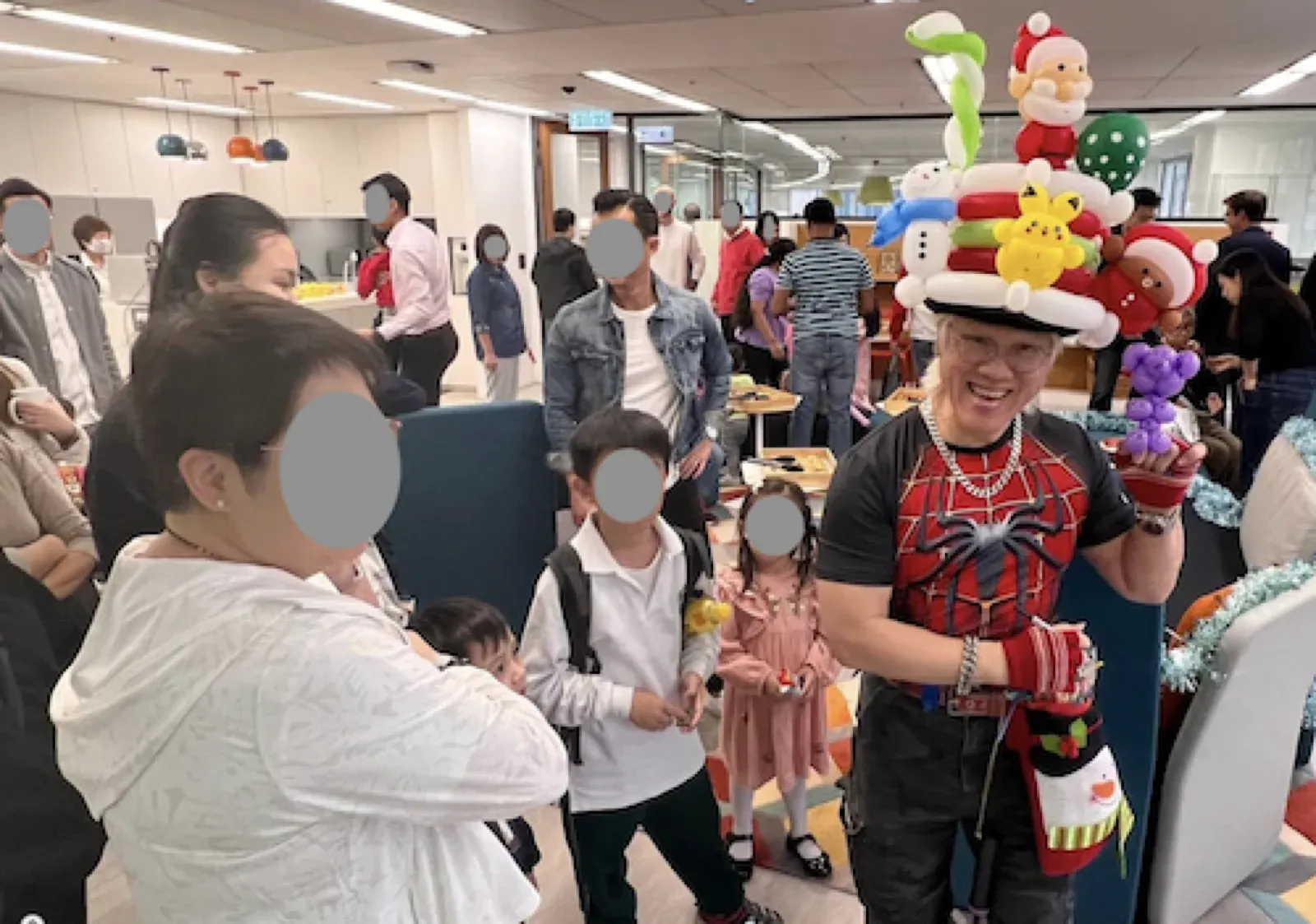 Balloon artist in a Christmas balloon hat entertaining families at an office party in Hong Kong