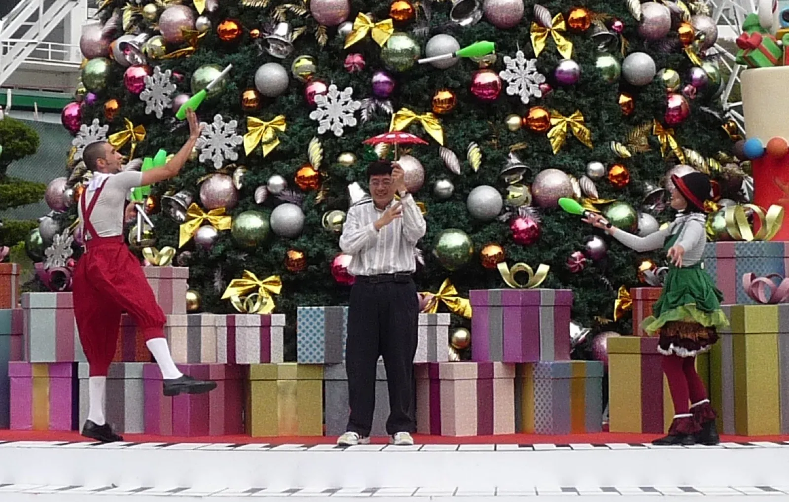 Performers on a Christmas show stage in front of a giant decorated Christmas tree