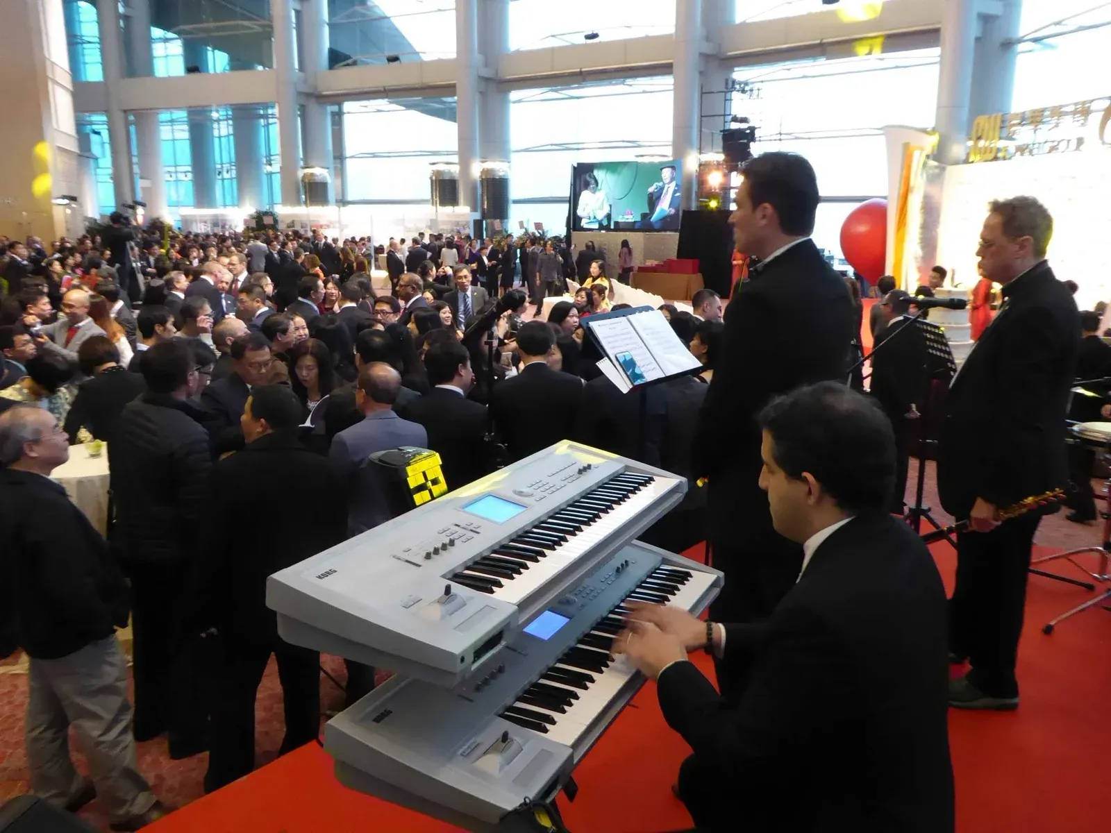 Musicians on keyboards performing for a crowd at a corporate cocktail event in Hong Kong