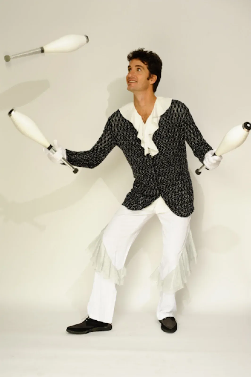 Juggler in a black and white costume juggling clubs