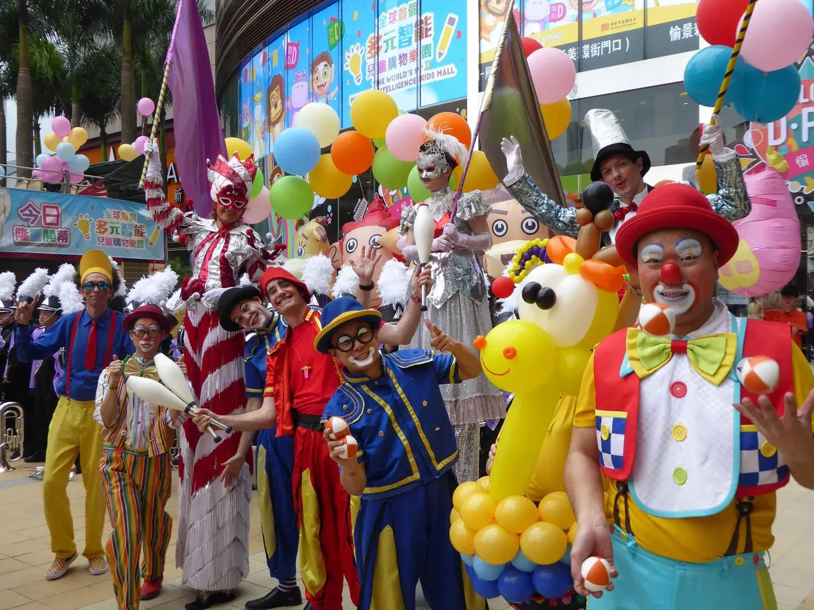 Circus parade with clowns, jugglers, stilt walkers and a unicycle rider in a shopping mall