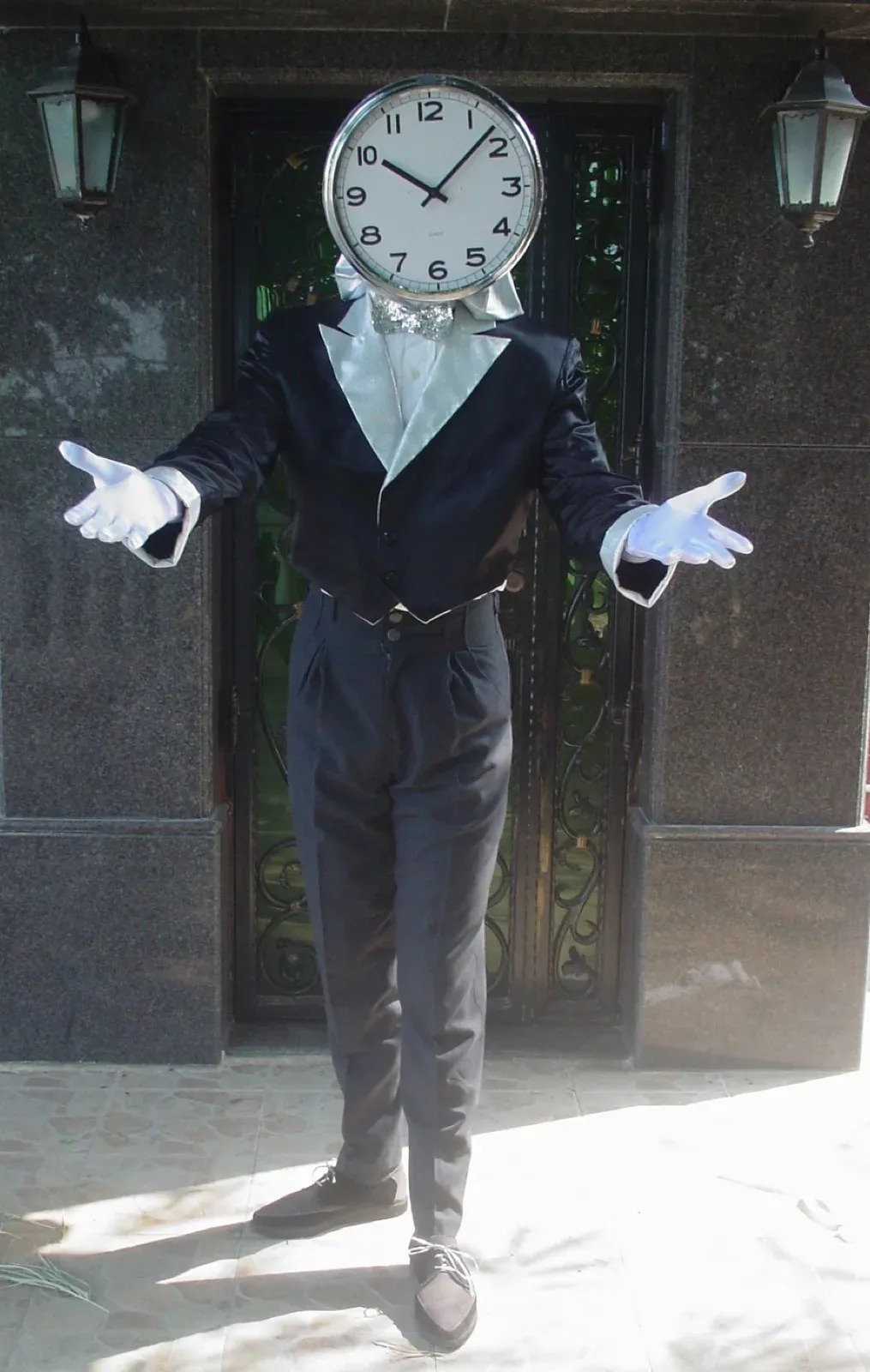 Mime with a clock face for a head in a black suit and white gloves