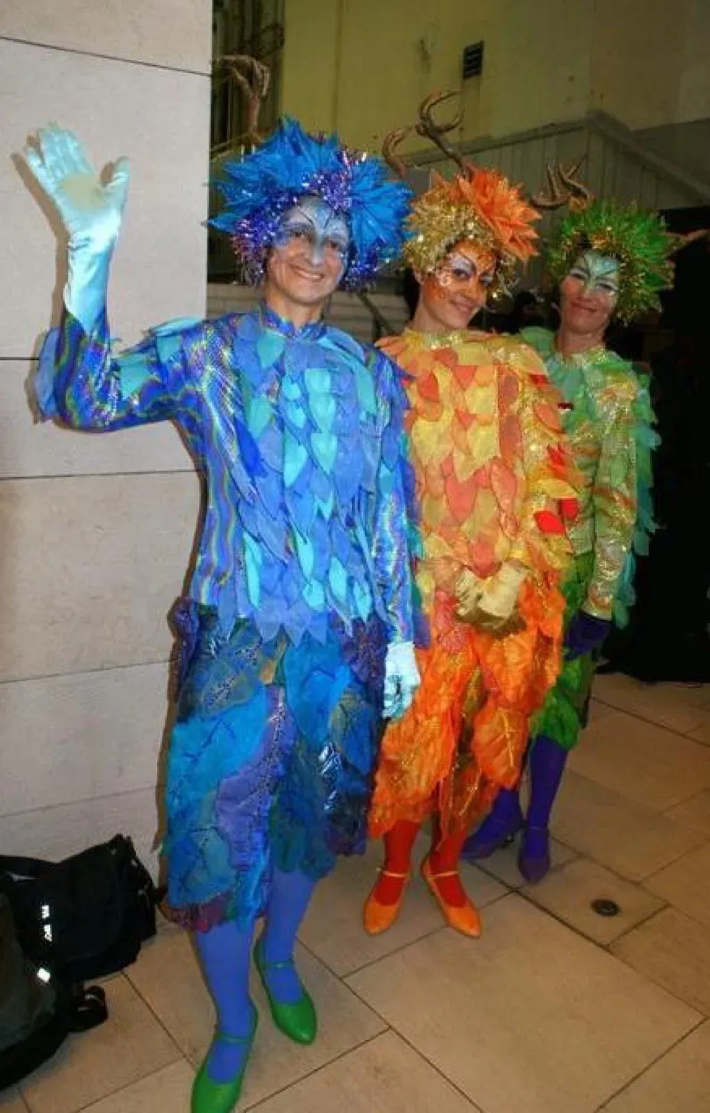Three performers in blue, orange and green leaf costumes at a Christmas event