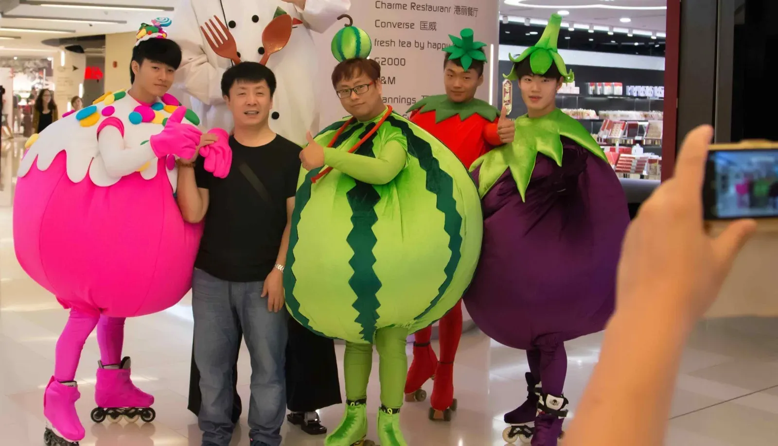 Fruit and vegetable characters, a pink dragon fruit, a watermelon and an aubergine, posing with guests