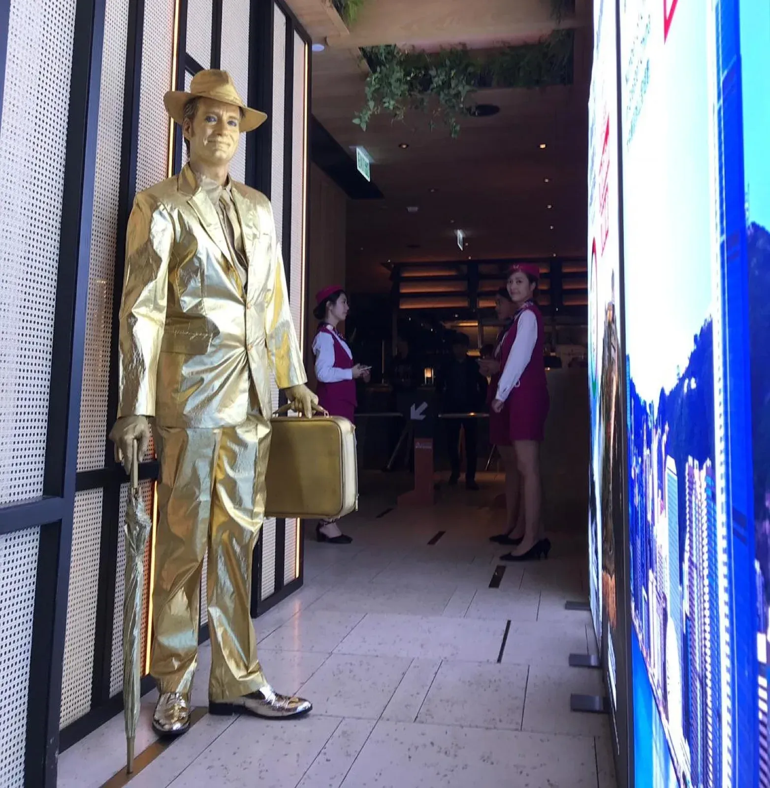 Gold living statue mime in a suit and hat holding a briefcase