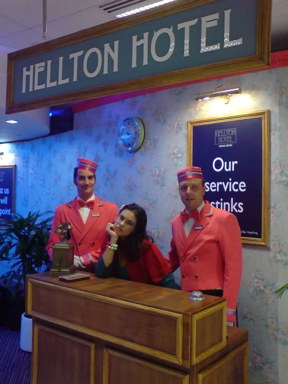 Comic actors as hotel staff at a Hellton Hotel reception desk set in Hong Kong