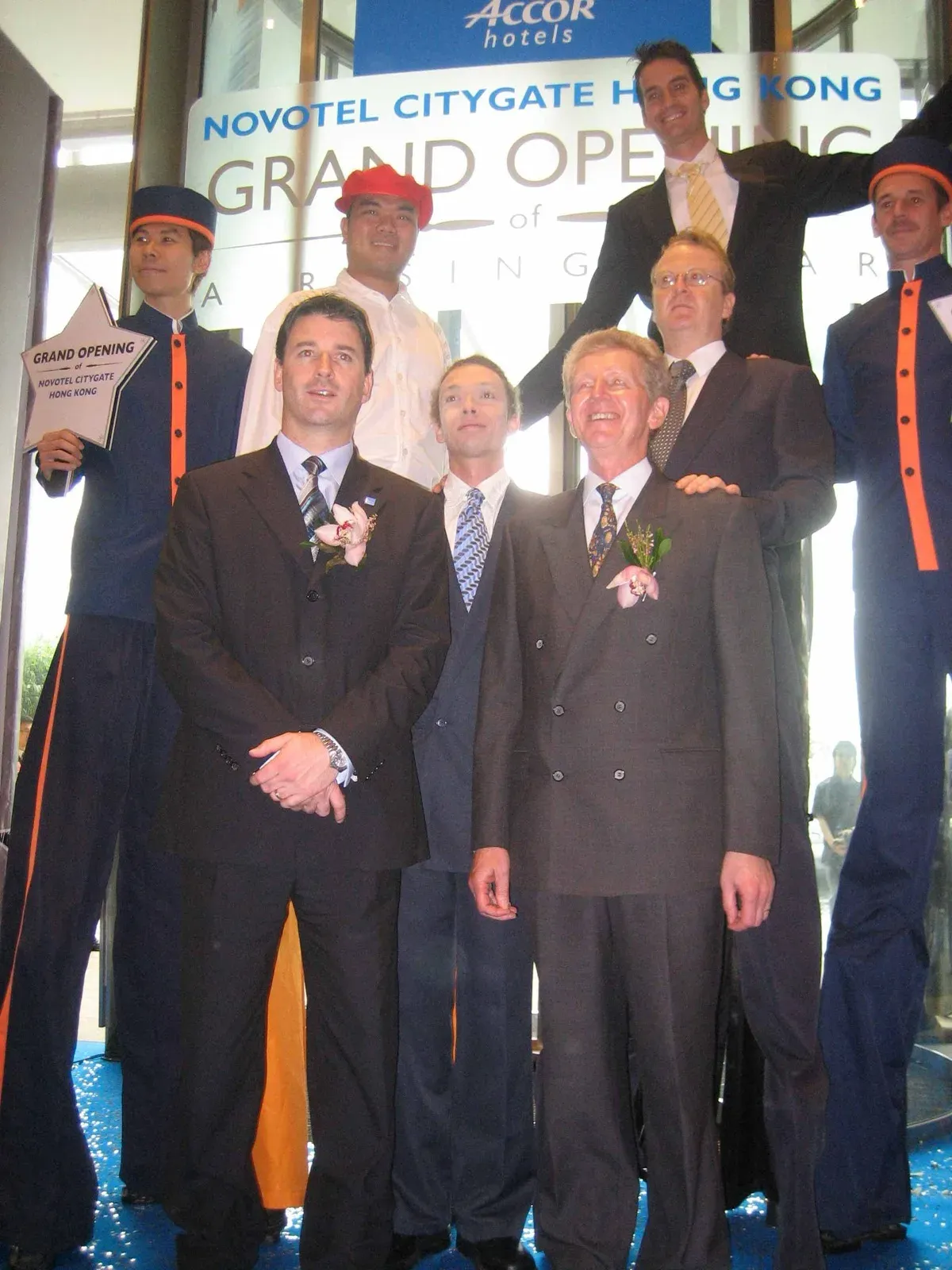 Stilt walkers and guests in suits at the Novotel Citygate grand opening