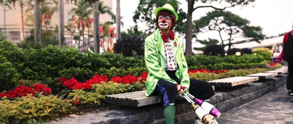 Clown juggler in a green suit with juggling clubs at an outdoor event in Hong Kong