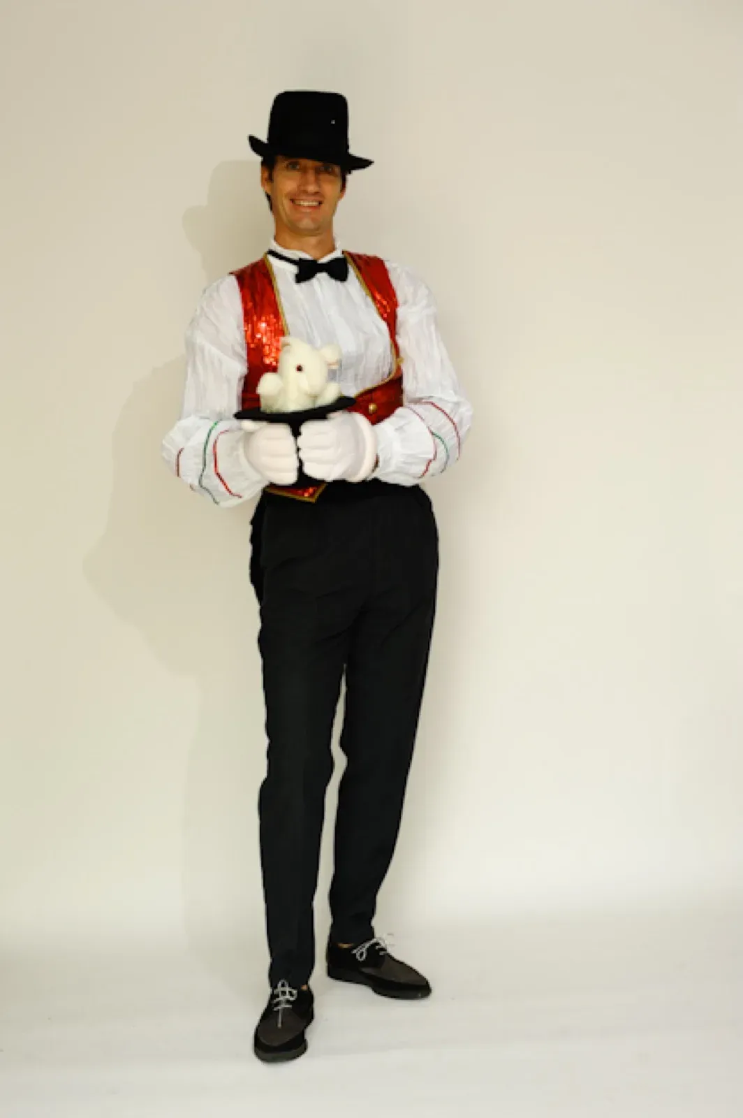 Magician in a black waistcoat, white shirt and top hat