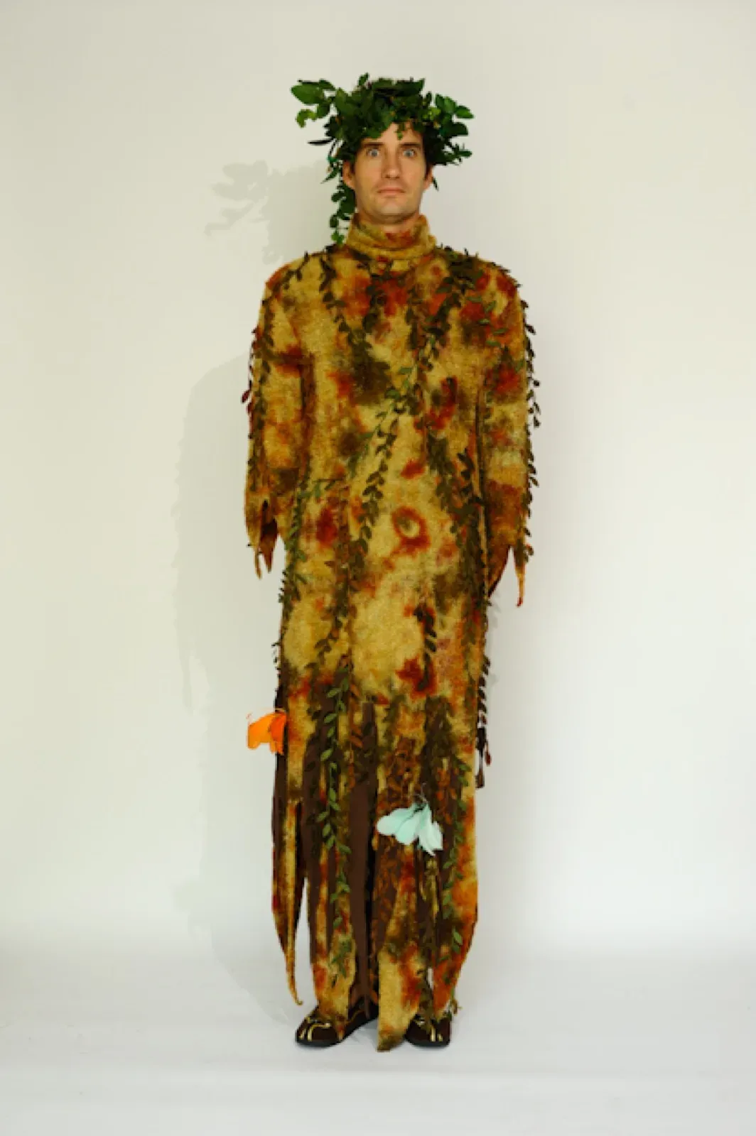 Performer in a tree costume of fabric leaves with a leafy crown