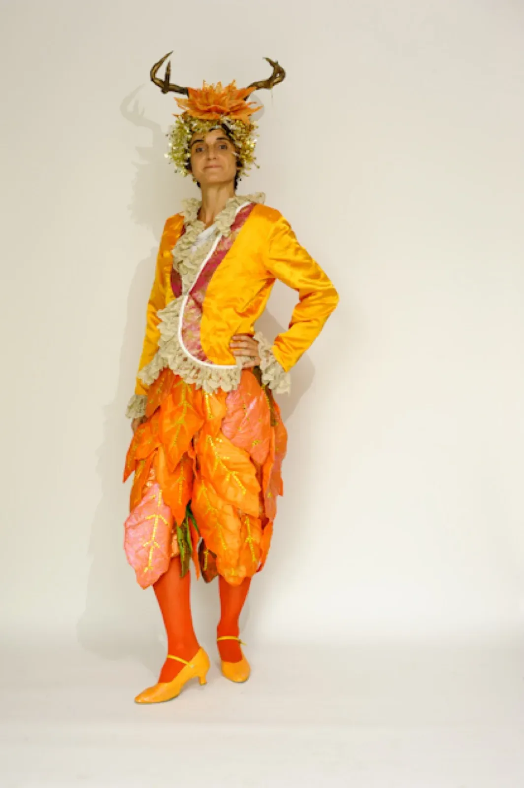Performer in a yellow jacket and orange leaf trousers with antlers
