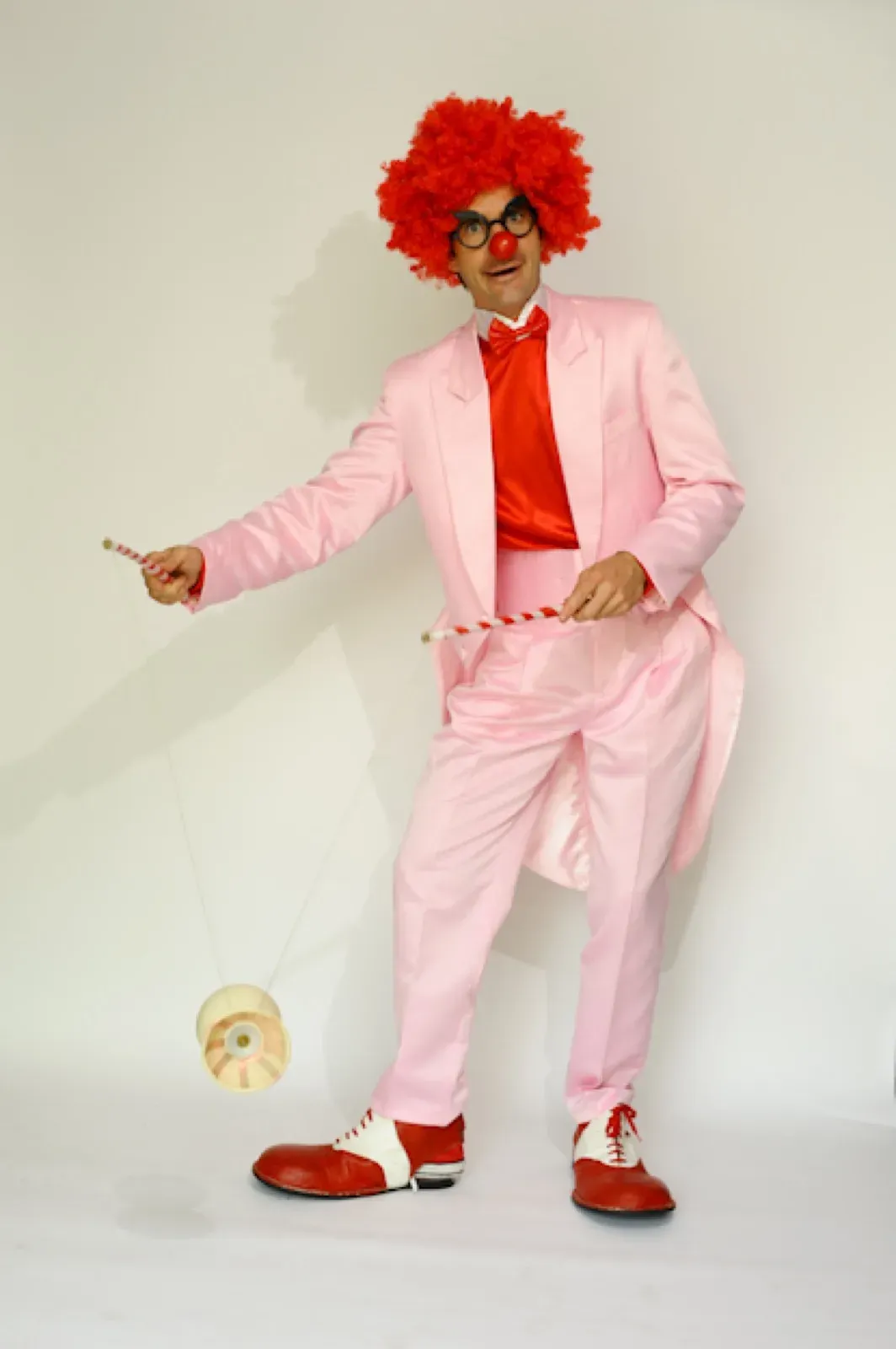 Clown in a pink tuxedo and a curly red wig