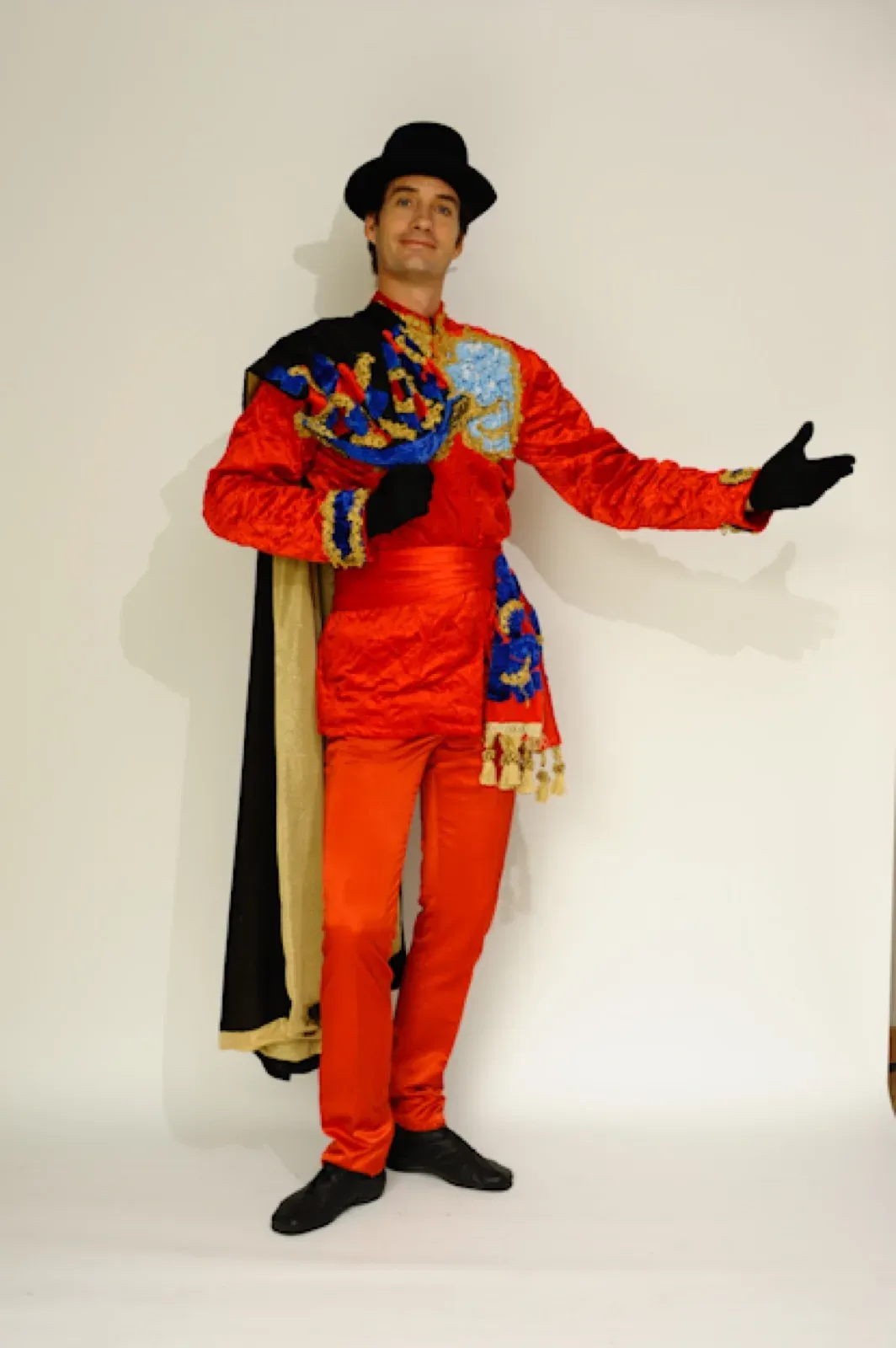 Performer in a red jacket with a black cape and a top hat
