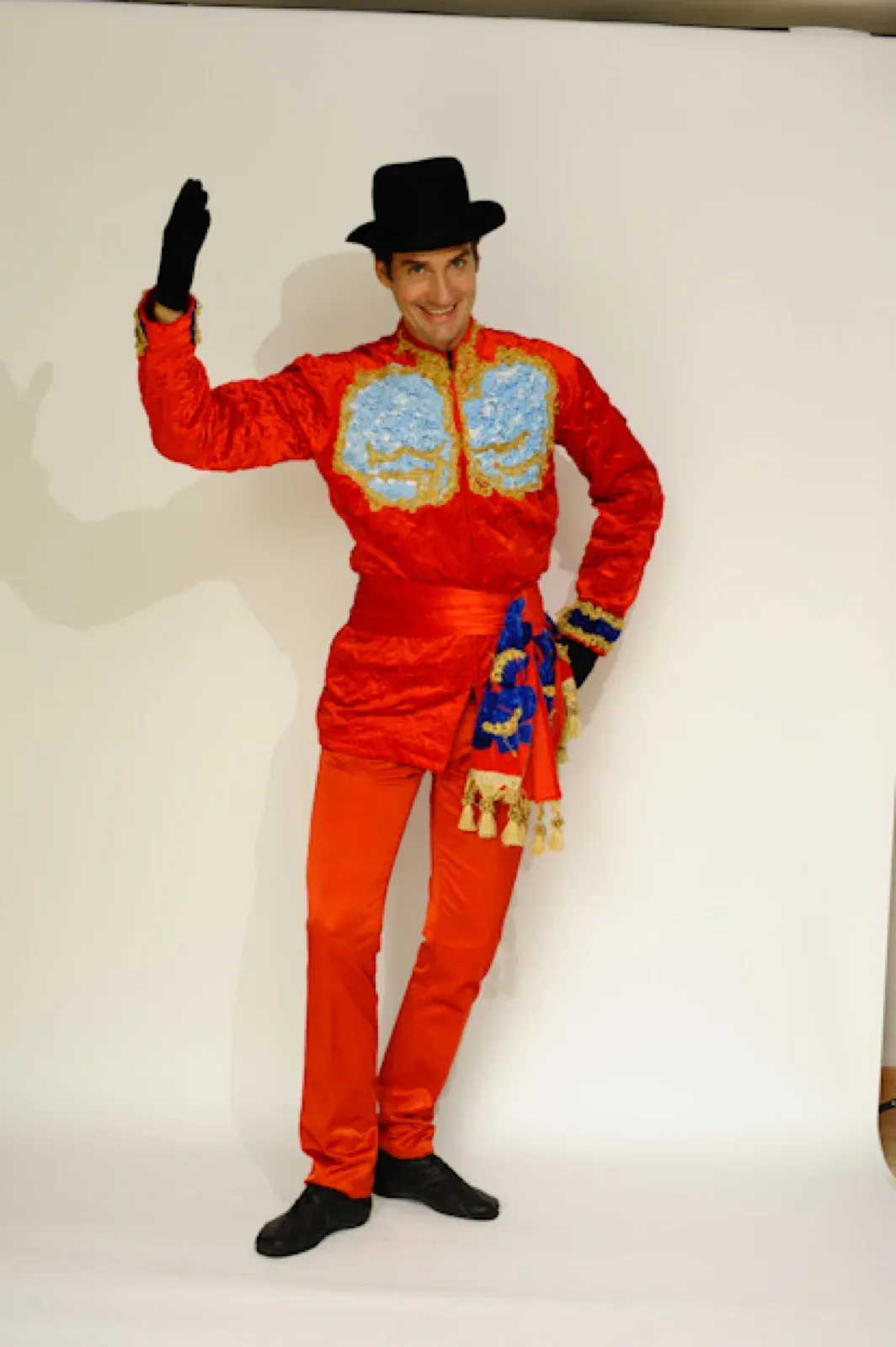 Performer in a red tamer jacket and trousers with a black top hat