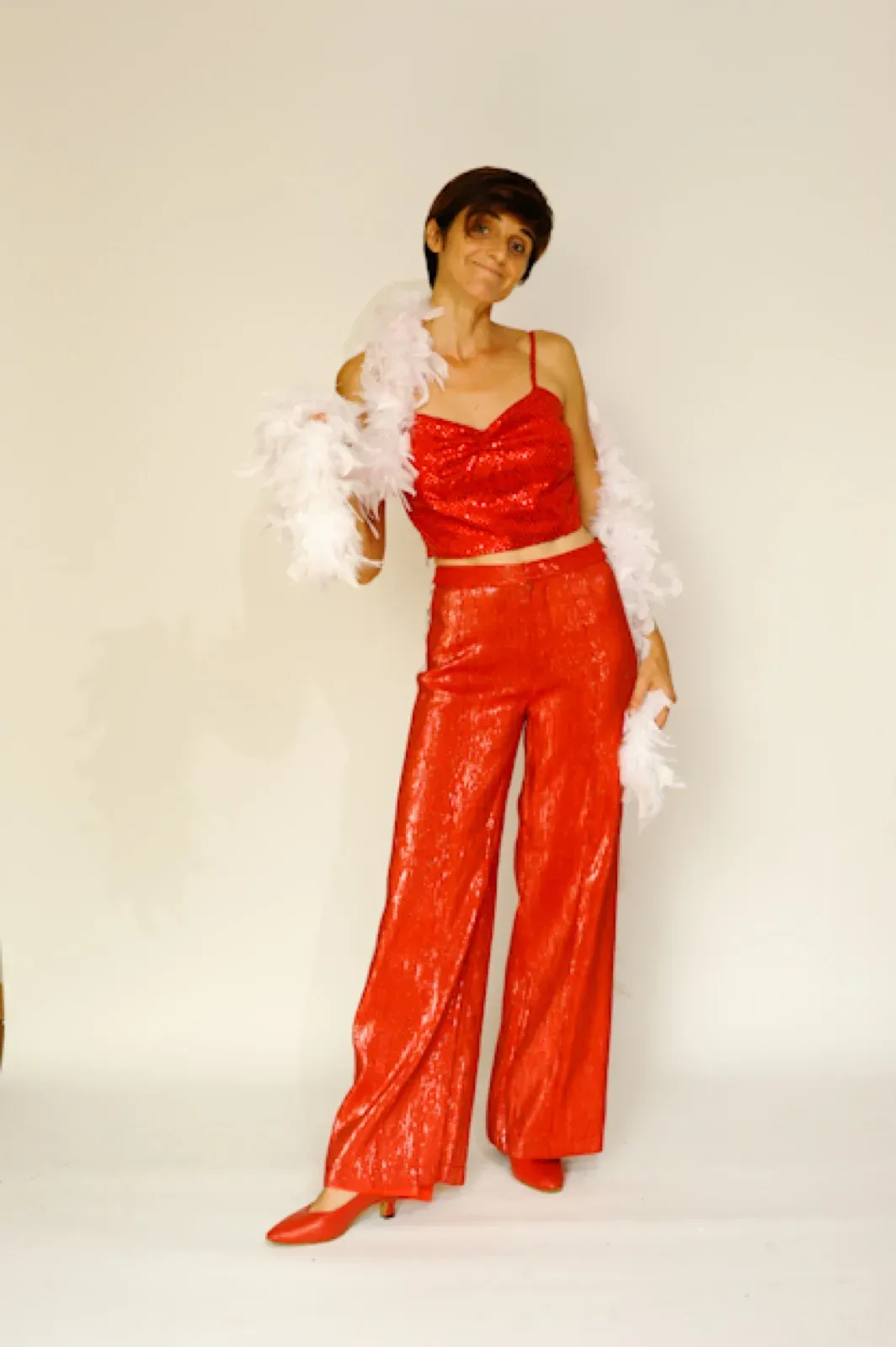 Performer in a red top and wide red trousers with a white feather boa