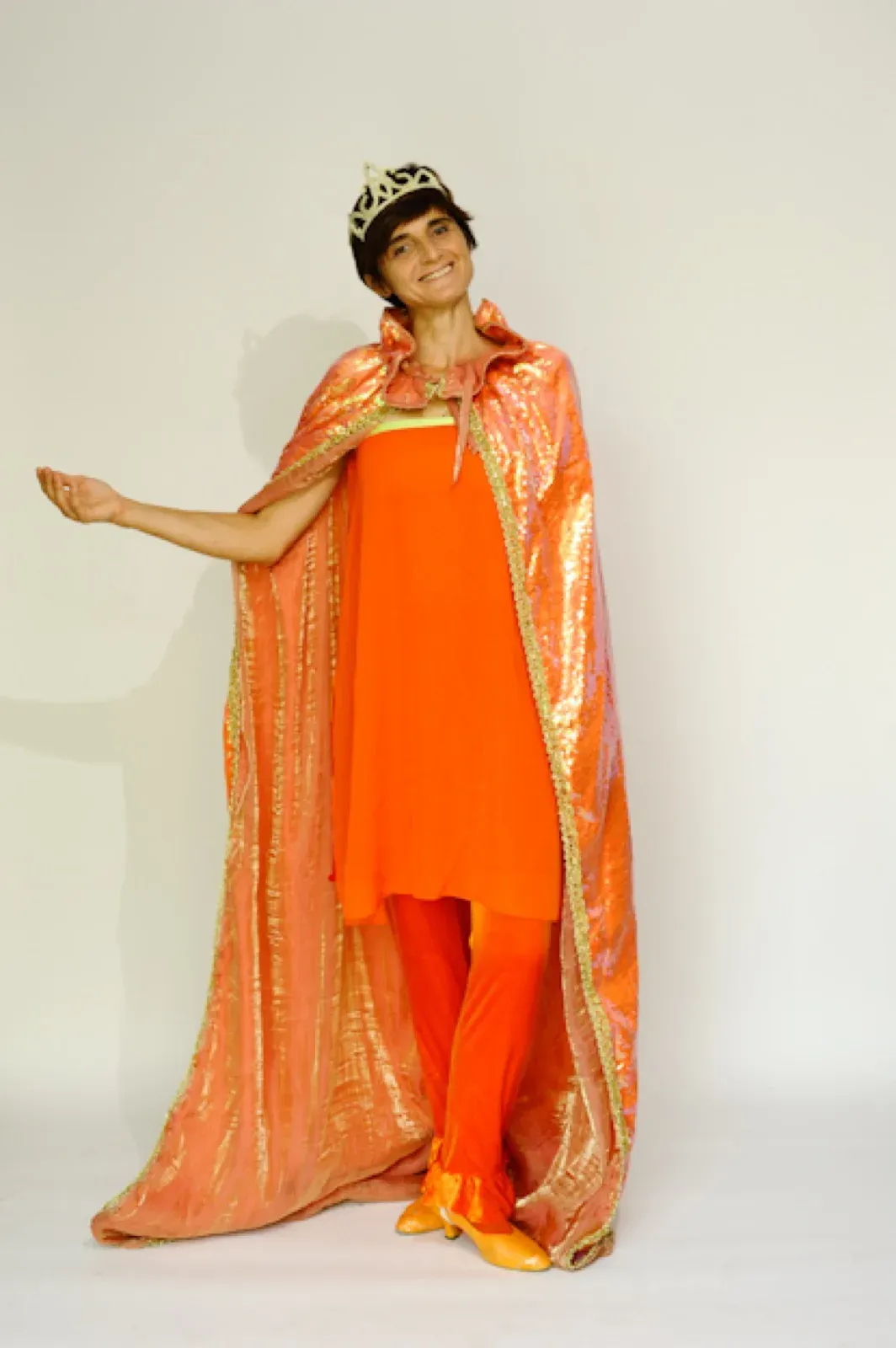 Performer in an orange dress with a long orange and gold cape and a tiara