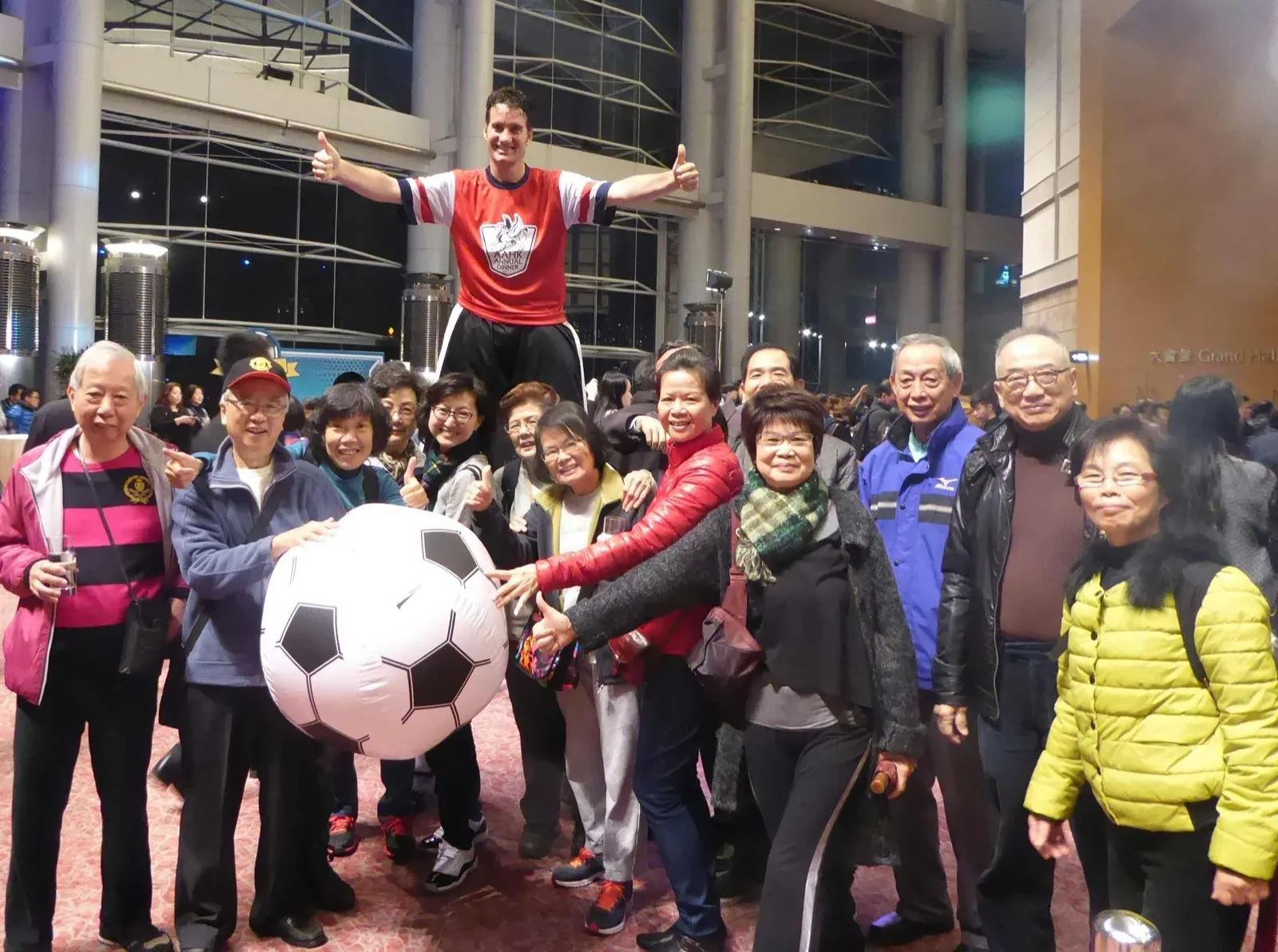 Footballer stilt walker with a giant football posing with a group of guests