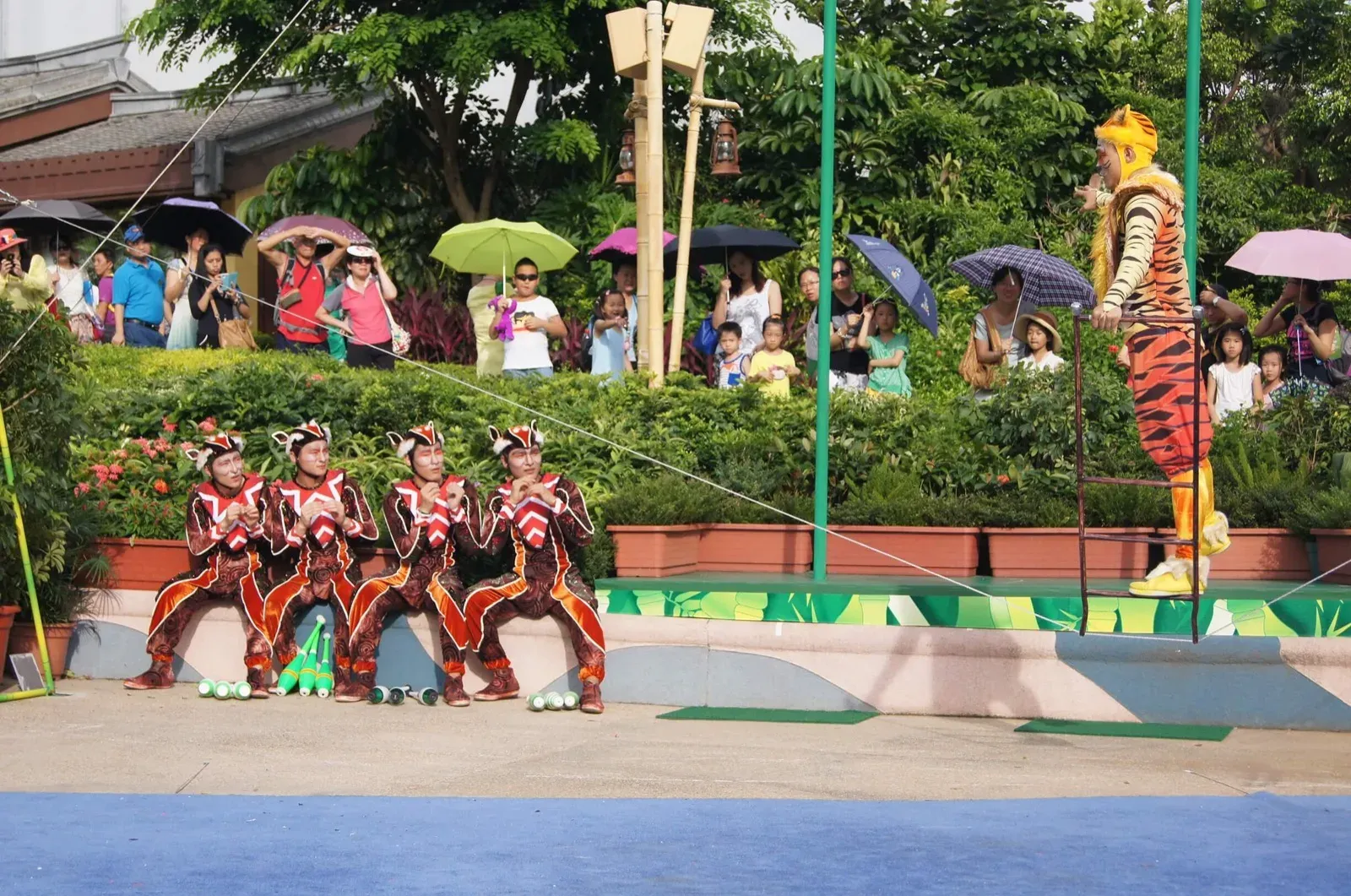 Acrobats in red costumes performing in a theme park garden in Hong Kong