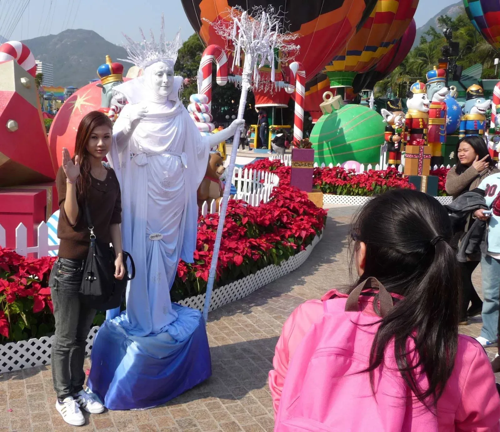 White statue mime with a trident posing with a visitor at a Hong Kong theme park