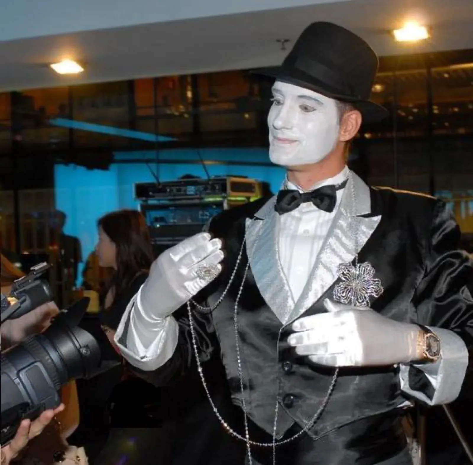 White-face mime in a tuxedo and top hat at a cocktail event