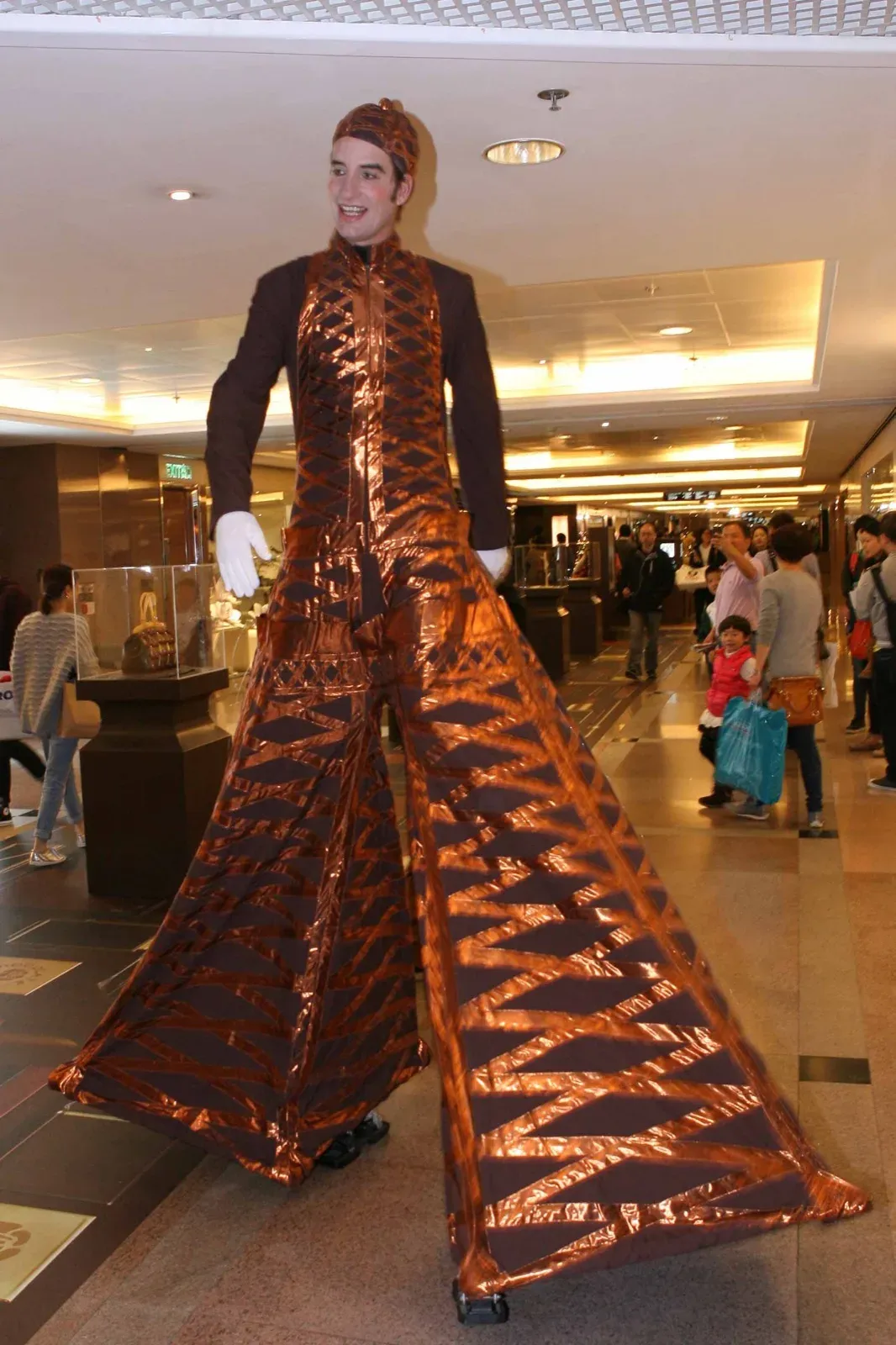 Stilts walker in a bronze Eiffel Tower costume at a shopping mall event in Hong Kong