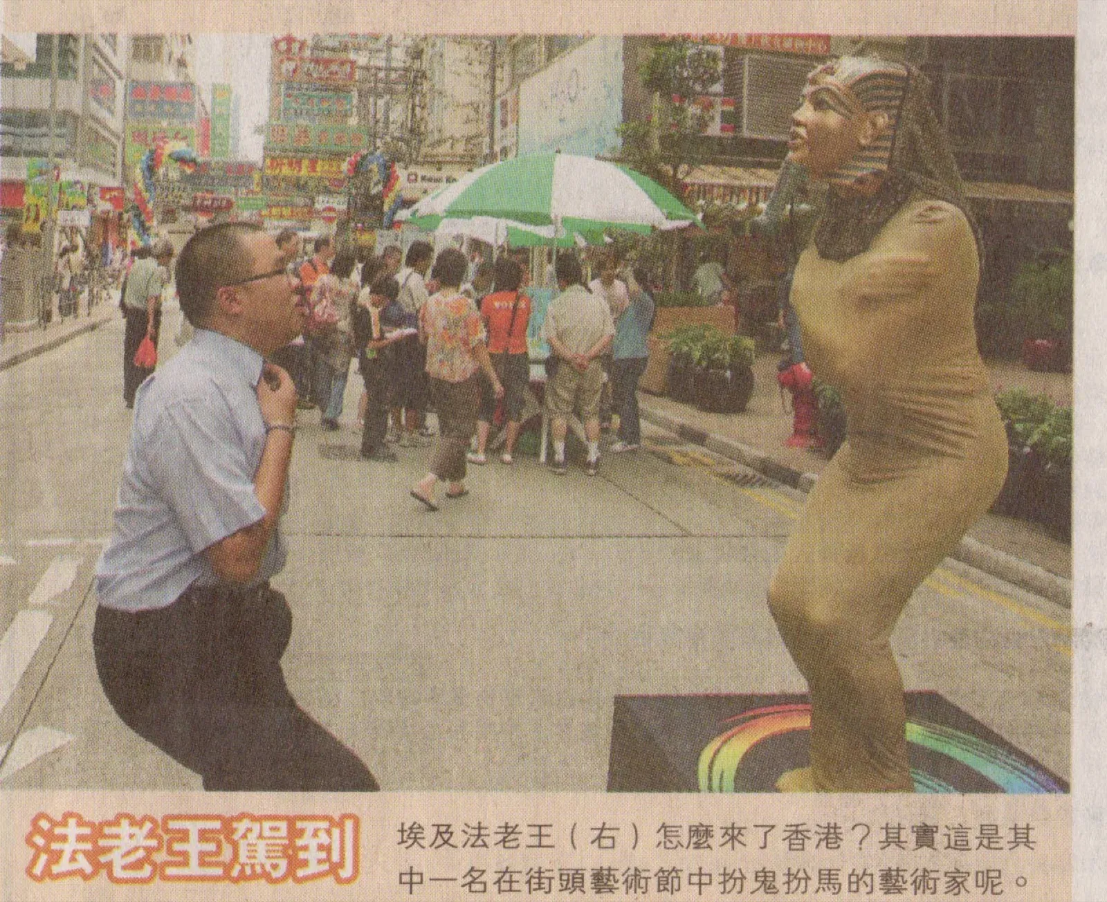 Newspaper photo of a gold statue mime surprising a passer-by in a Hong Kong street