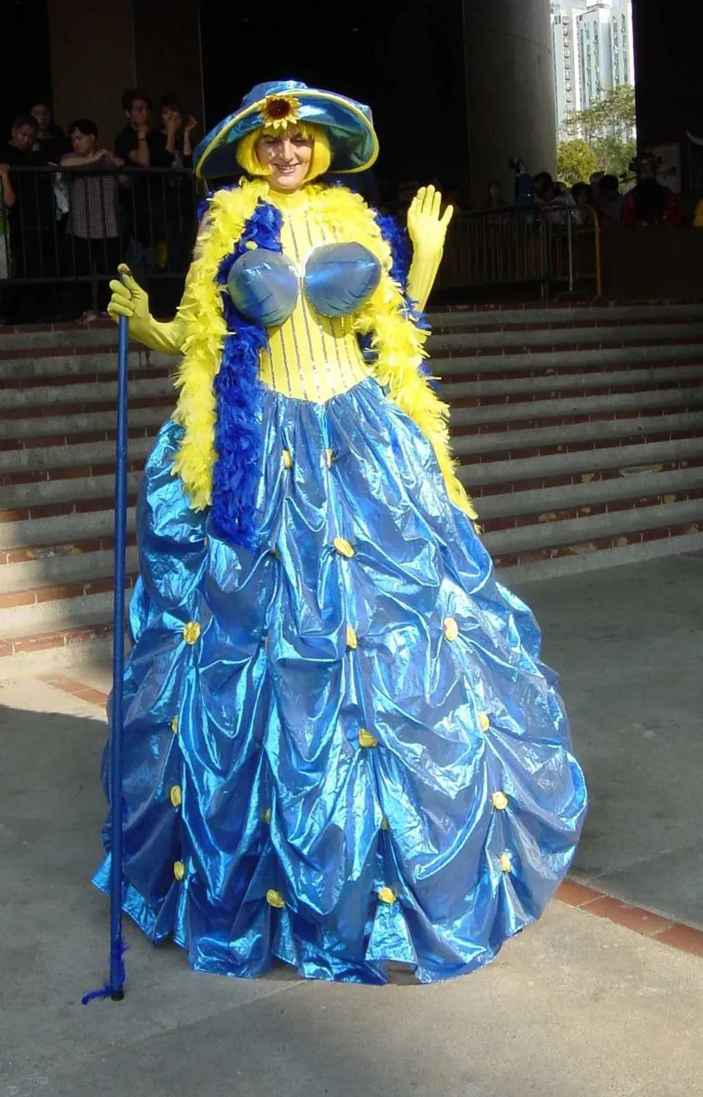 Stilt walker in a big blue and yellow gown and bonnet at a corporate cocktail event